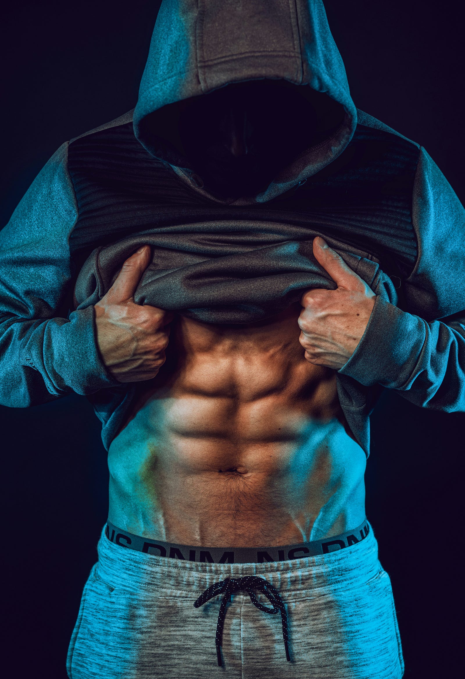 A man pulls up his shirt to reveal an abdominal six-pack.