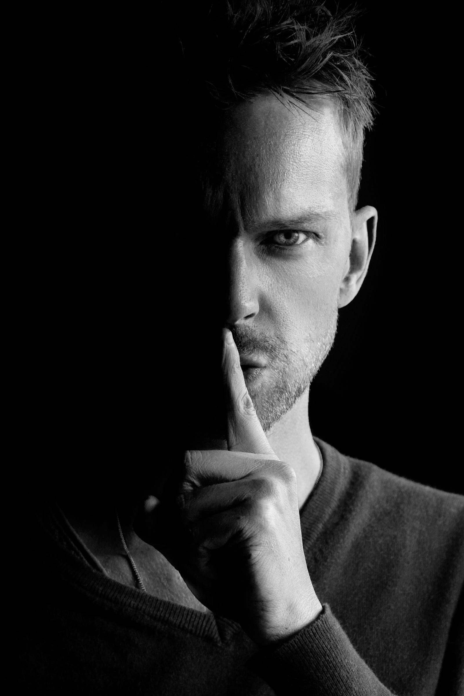 A man puts a single digit up to his mout in a “shh” motion. Privacy is critical when it comes to artificial intelligence and health care information extraction.