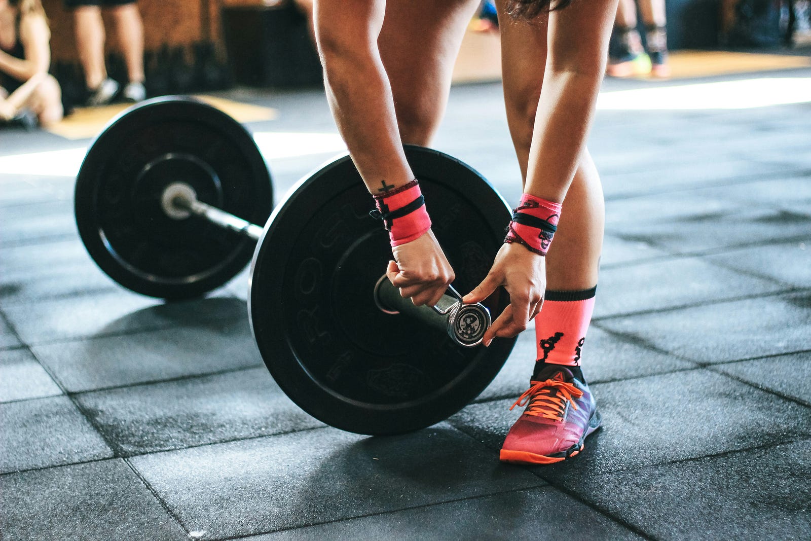 A person places collars on a barbell loaded with two weights.