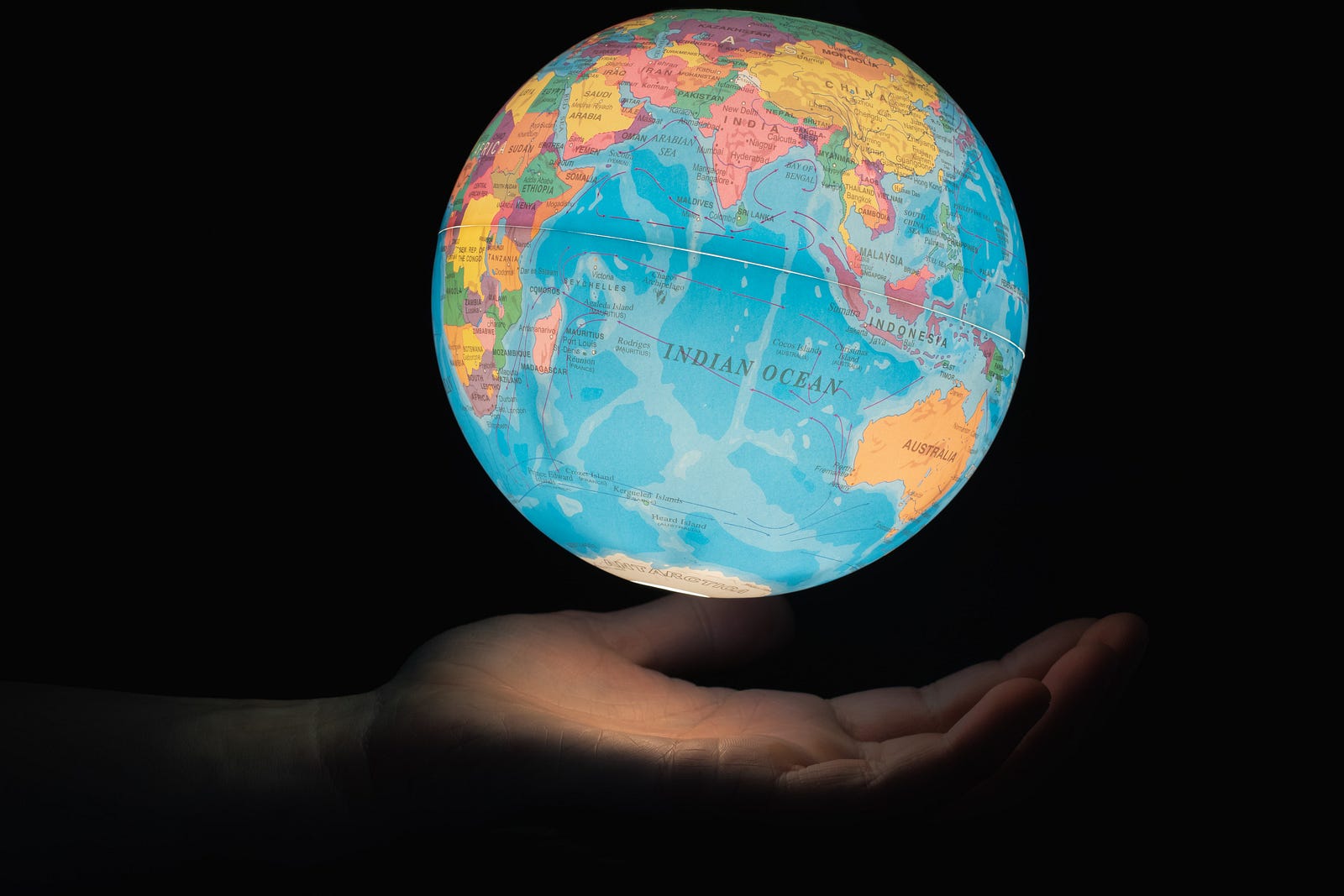 A hand reaches out from the left as an illuminated globe floats above it. There is a black background. Preliminary wastewater testing in the United States has detected the new highly mutated coronavirus variant BA.2.86.