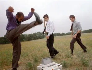 Screen shot of the movie Office Space, with three men in a field destroying a printer.