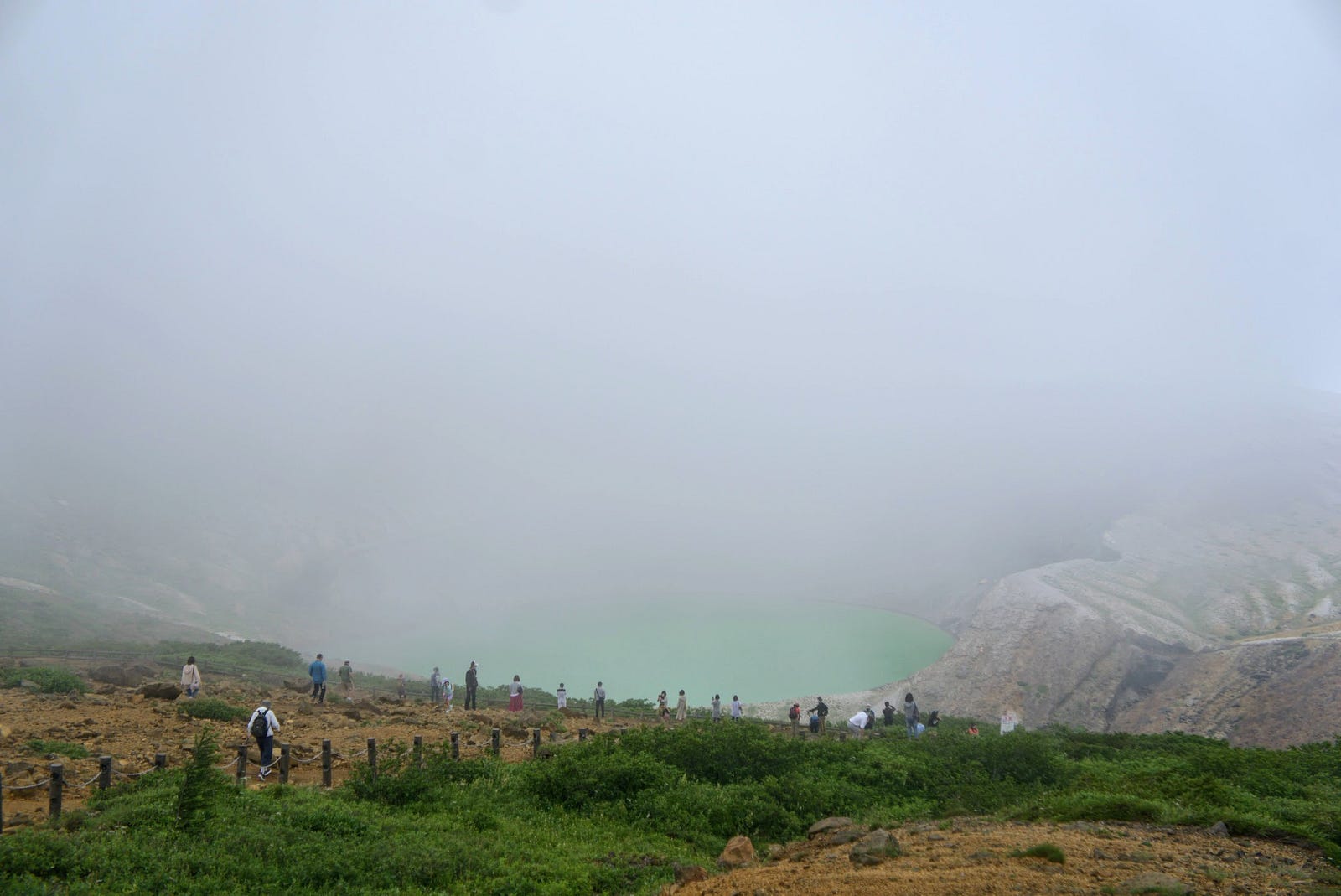 Onlookers surround the emerald green ‘Okama’ crater lake of Zao-san (Mt. Zao) surrounded in a thick cloud.