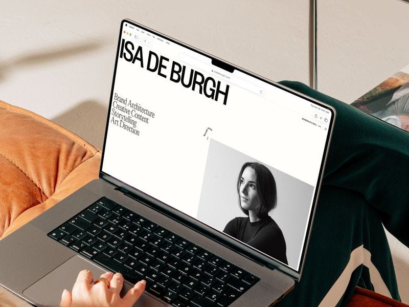 Laptop displaying Isa de Burgh’s portfolio website with clean typography and a portrait image, set in a calm, minimal workspace environment.