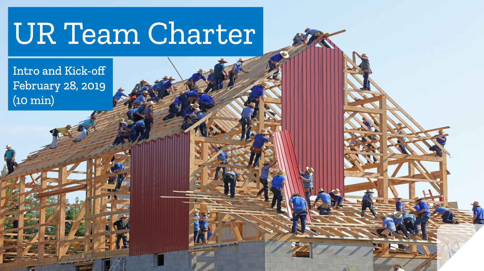 Photo of several dozen people building the frame of a large building