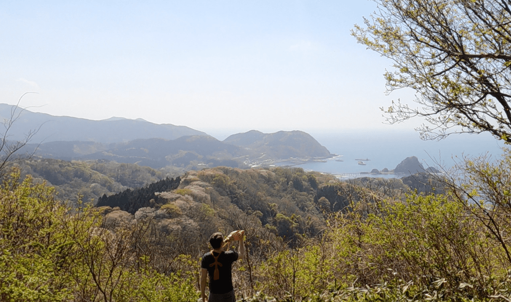 A Yamabushi plays his conch as he looks over Yura and Hakusan island from a lookout on the way to Mt. Arakura