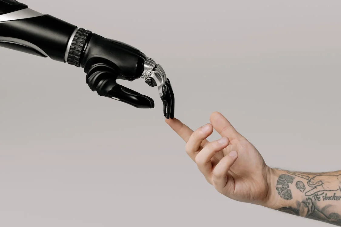 https://www.pexels.com/photo/bionic-hand-and-human-hand-finger-pointing-6153354/