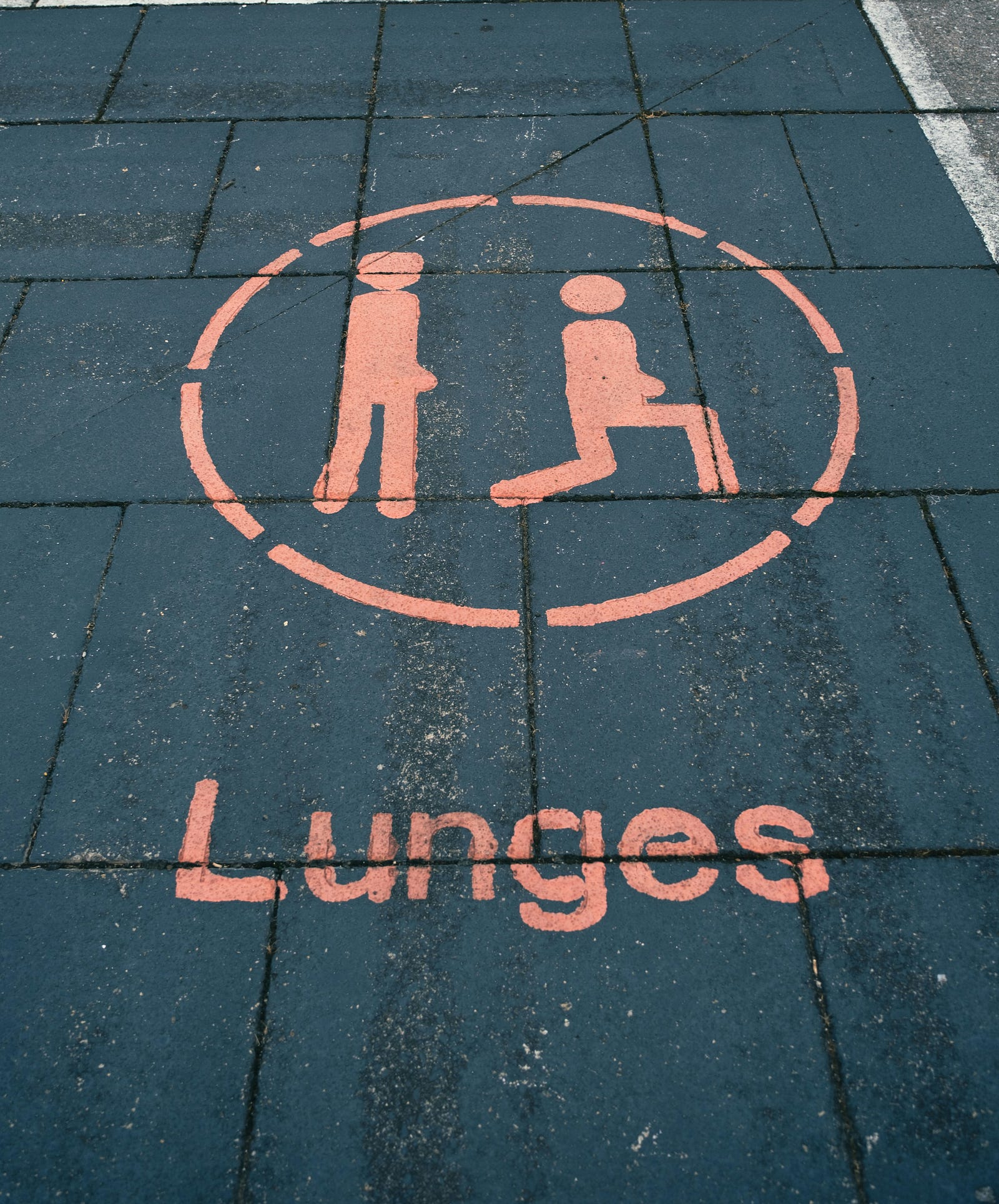 A cartoon of a person standing and then lunging is painted on a street. Walking lunges are a form of dynamic stretching.