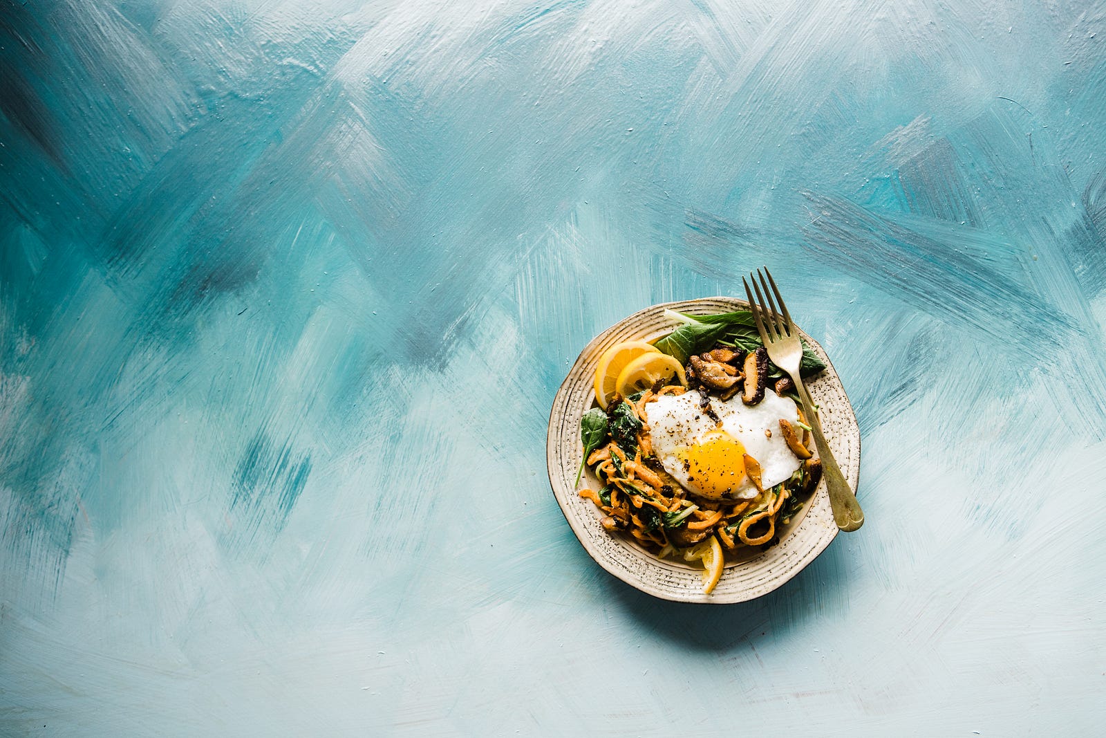 A plate of food in the right lower quadrant with a painted blue background. The swaths of paint are readily visible. The Mediterranean and MIND diets appear to reduce dementia risk.