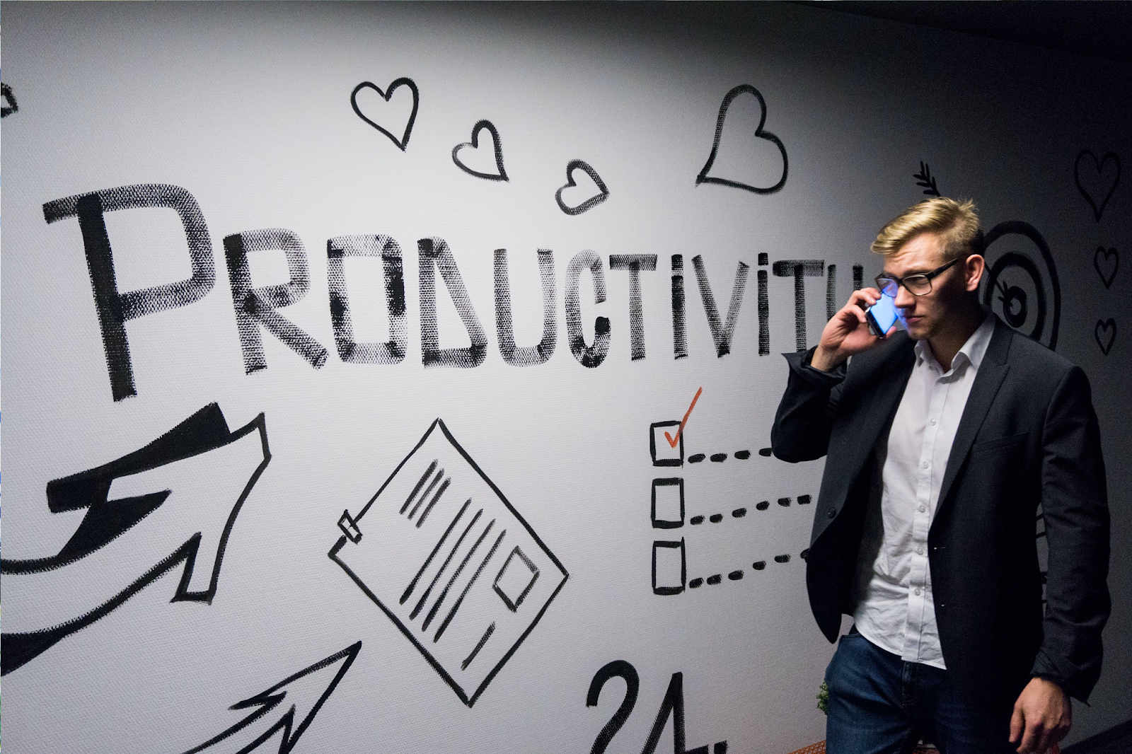 man on phone walking past wall with productivity written on it