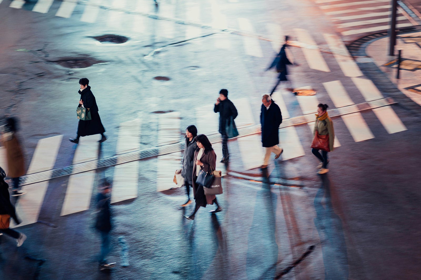 Several Asian people cross a crosswalk.