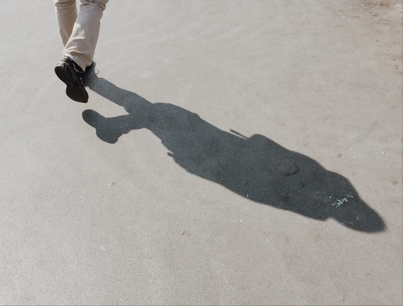 A person walks away from us. We only see her lefs from calf level down. Her shadow dominates the image, extending from upper left to lower right. Otherwise empty gray image. The COVID-19 pandemic caused many to move less. Are we recovering?