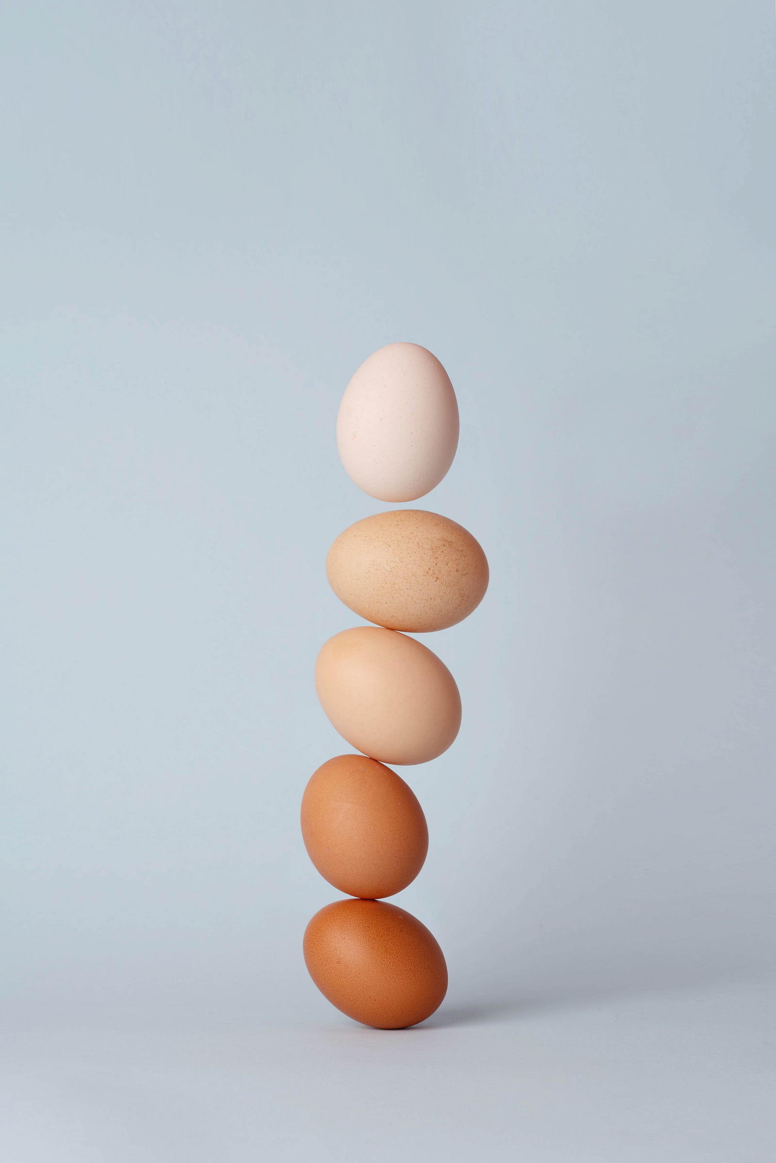 Five eggs are perched vertically on one another. The eggs range from very dark at the bottom to white at the top. There is a gray-blue background. Ten to 35 percent of your calories should come from protein. If you need 2,000 calories, that translates to 200 to 700 calories from protein (or 50 to 175 grams).