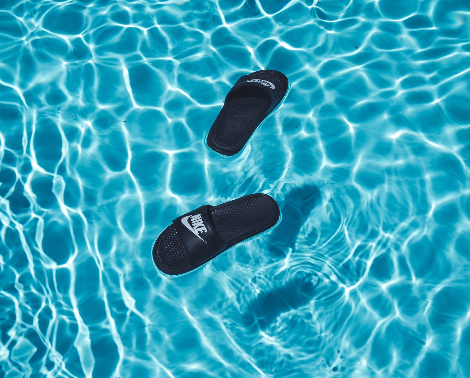 A pair of Nike sandals float in a sun-speckled swimming pool. A randomized study revealed the following results: Injury risk was greater in recreational runners who trained in the shoe version with greater cushioning stiffness (Stiff) than those using the soft version.