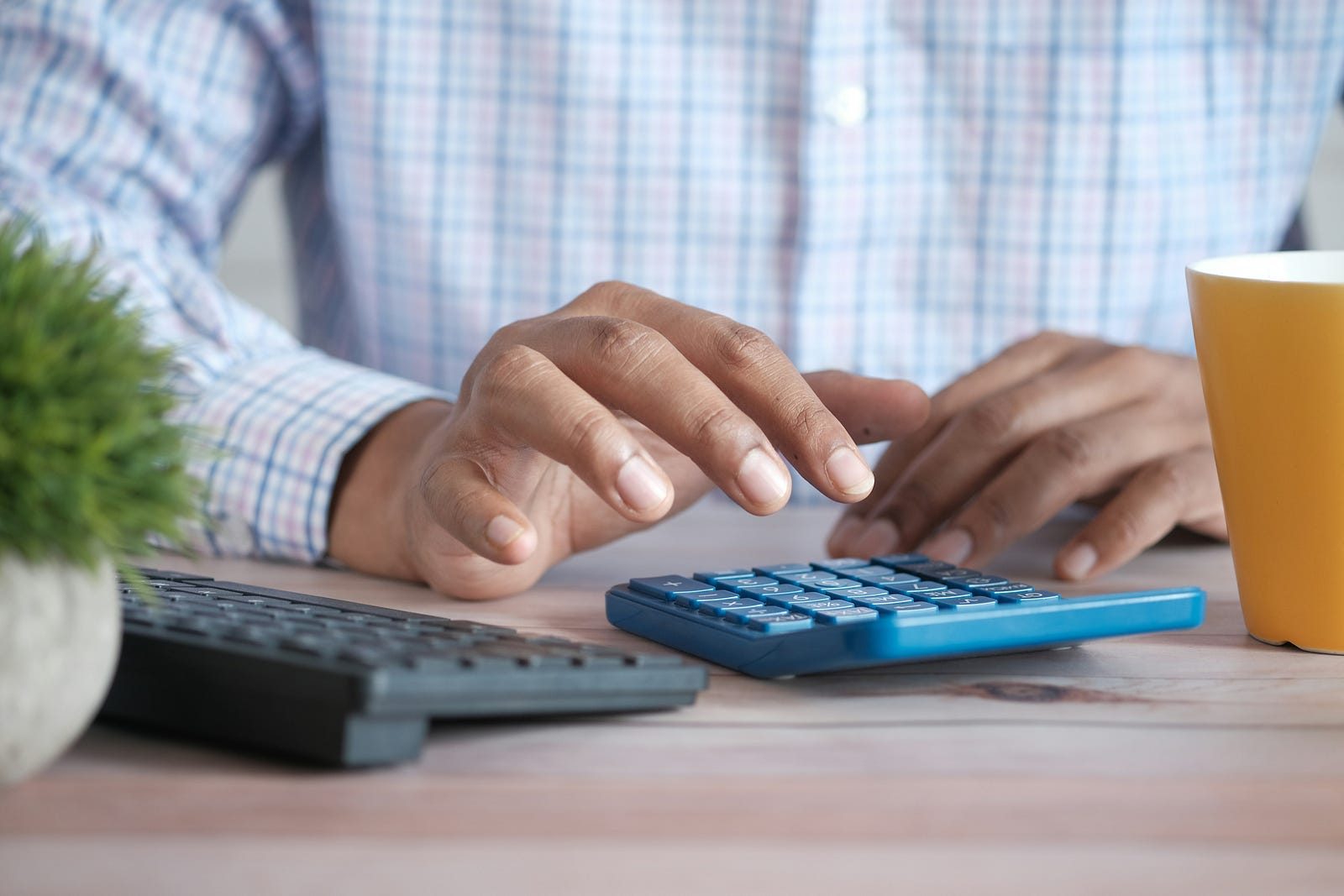 A person taps the keys of a blue calculator.