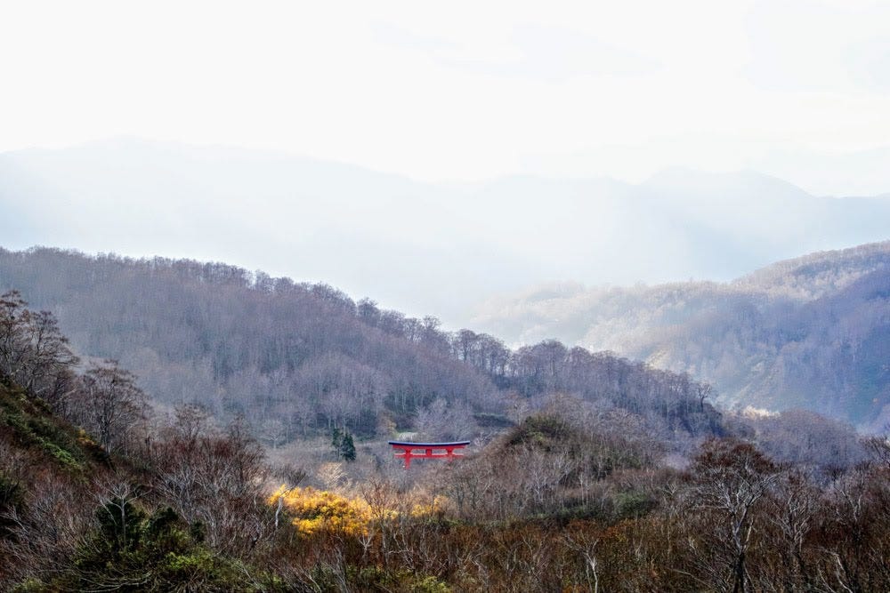 The Torii Shrine Gates of Mt. Yudono are visible in the distance in this picture of mountains in the middle of autumn