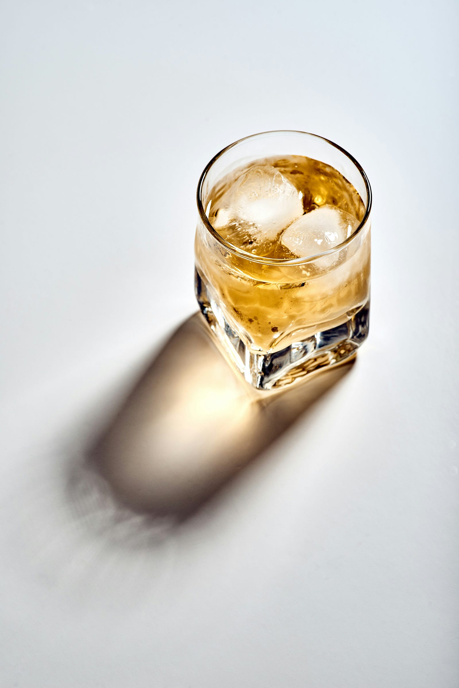 A square-bottomed clear glass of amber-colored alcohol. Alcohol raises colon cancer risk.