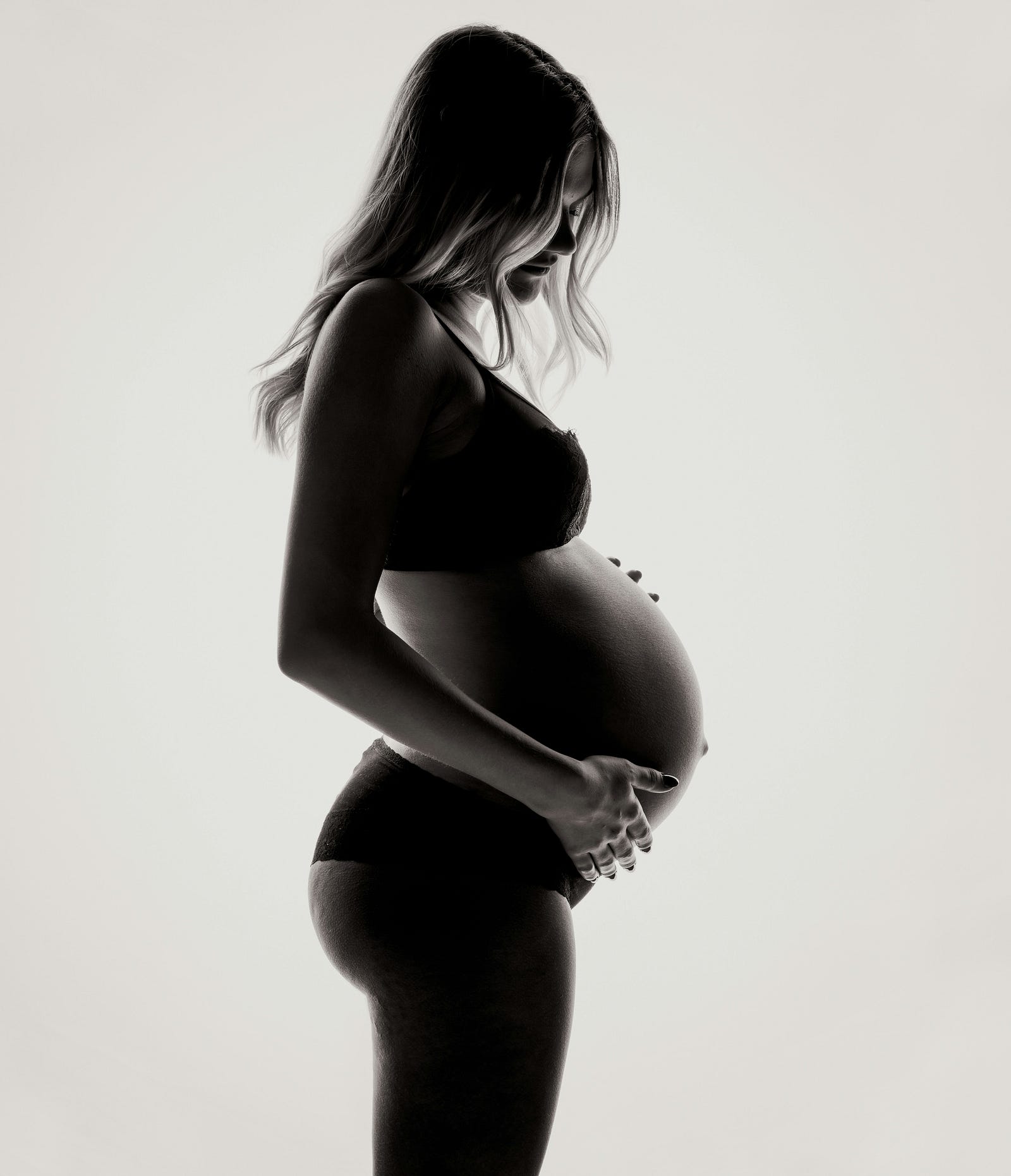 A young pregnant white woman in profile, her belly exposed.