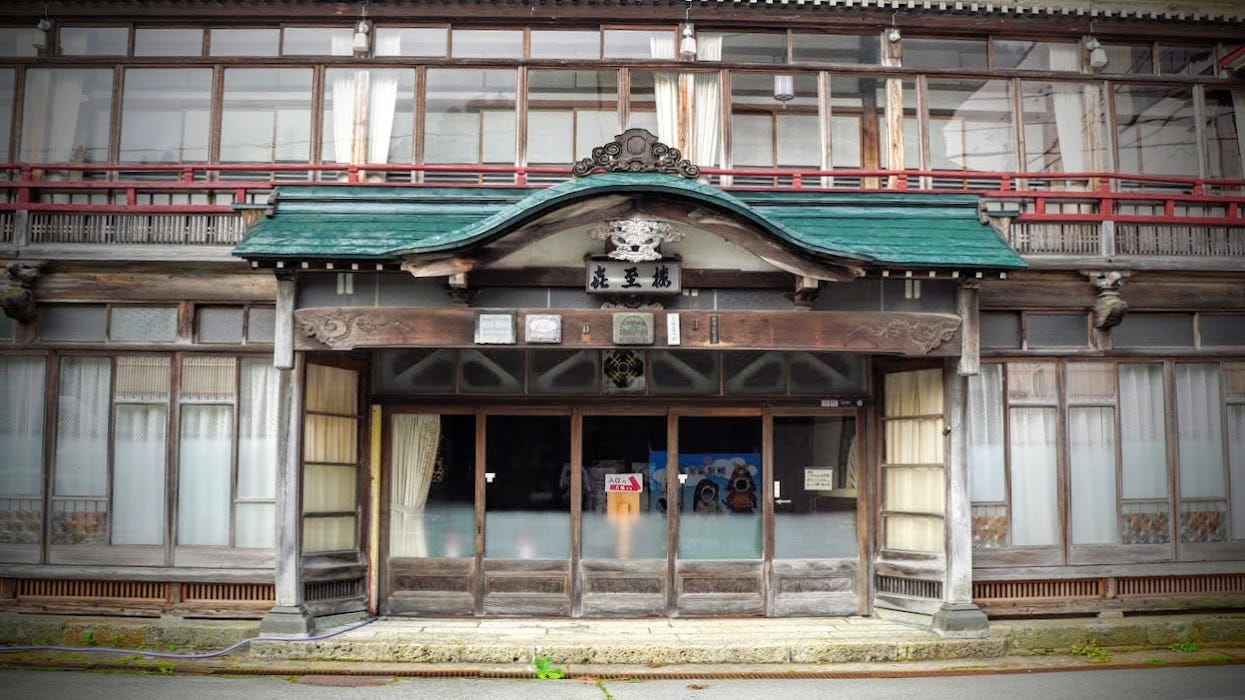 A green entrance roof over a giant wooden Ryokan in Semi Onsen