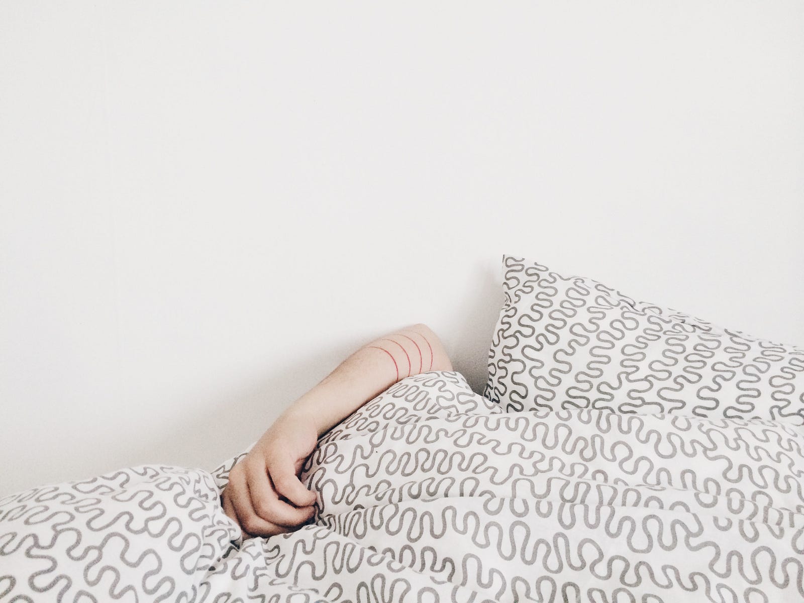 A left arm reaches around a black and white blanket. White background wall. People who slept less than five hours a night on average were three times more likely to have a stroke than those who got seven hours of sleep. On the other hand, sleeping more than nine hours appeared to be associated with a doubling in stroke risk (compared with those getting seven hours).
