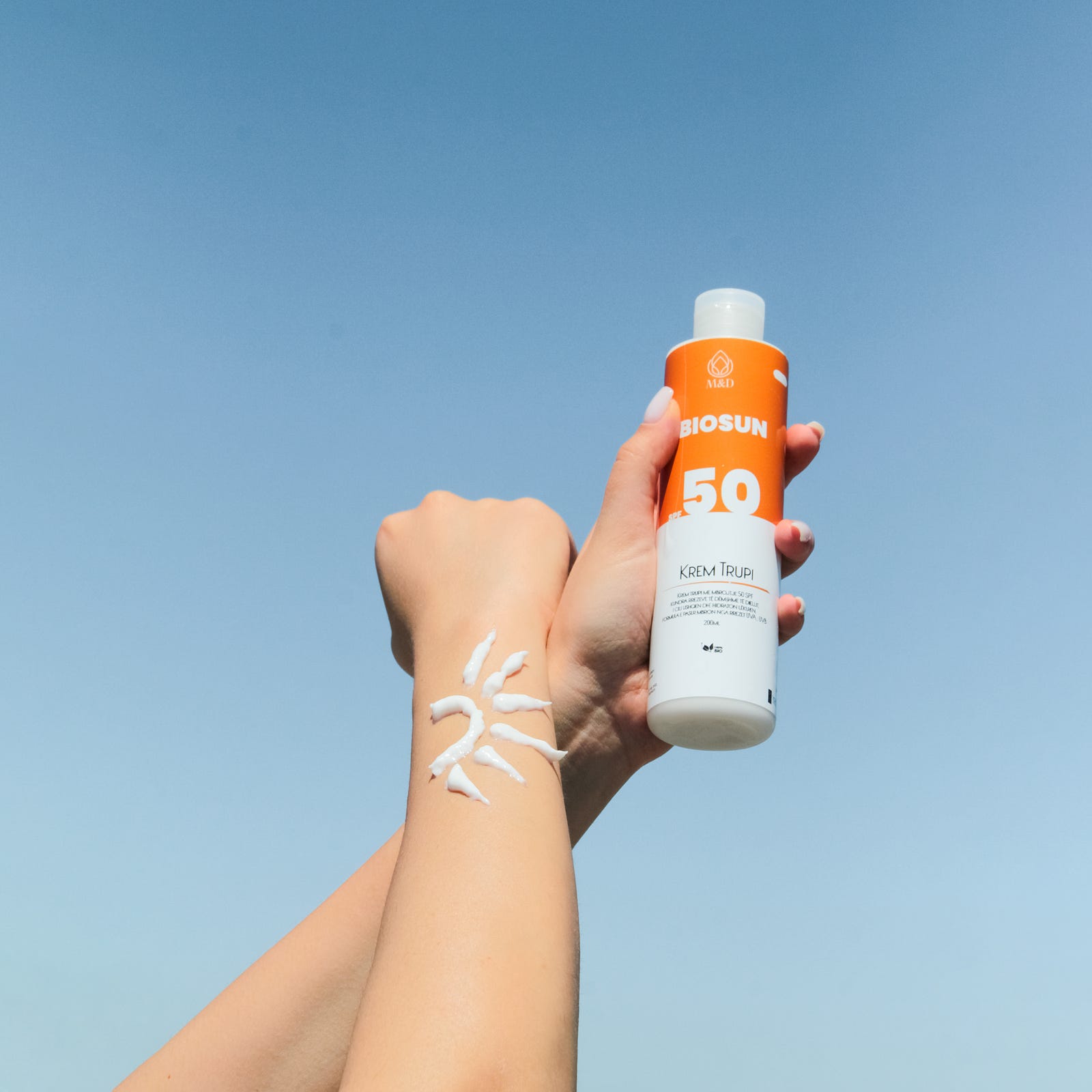 A left hand rises to hold an SPF 50 sunscreen bottle. To obtain the EWG mark, the item must be “green,” with little danger to health or the environment. The product must list each ingredient on the label, including nanoparticles and fragrances. It cannot contain ingredients restricted by the European Union and Canada, as well as the FDA, the US Environmental Protection Agency, the US National Toxicology Program, and California’s Proposition 65 list of known carcinogens and reproductive toxins.