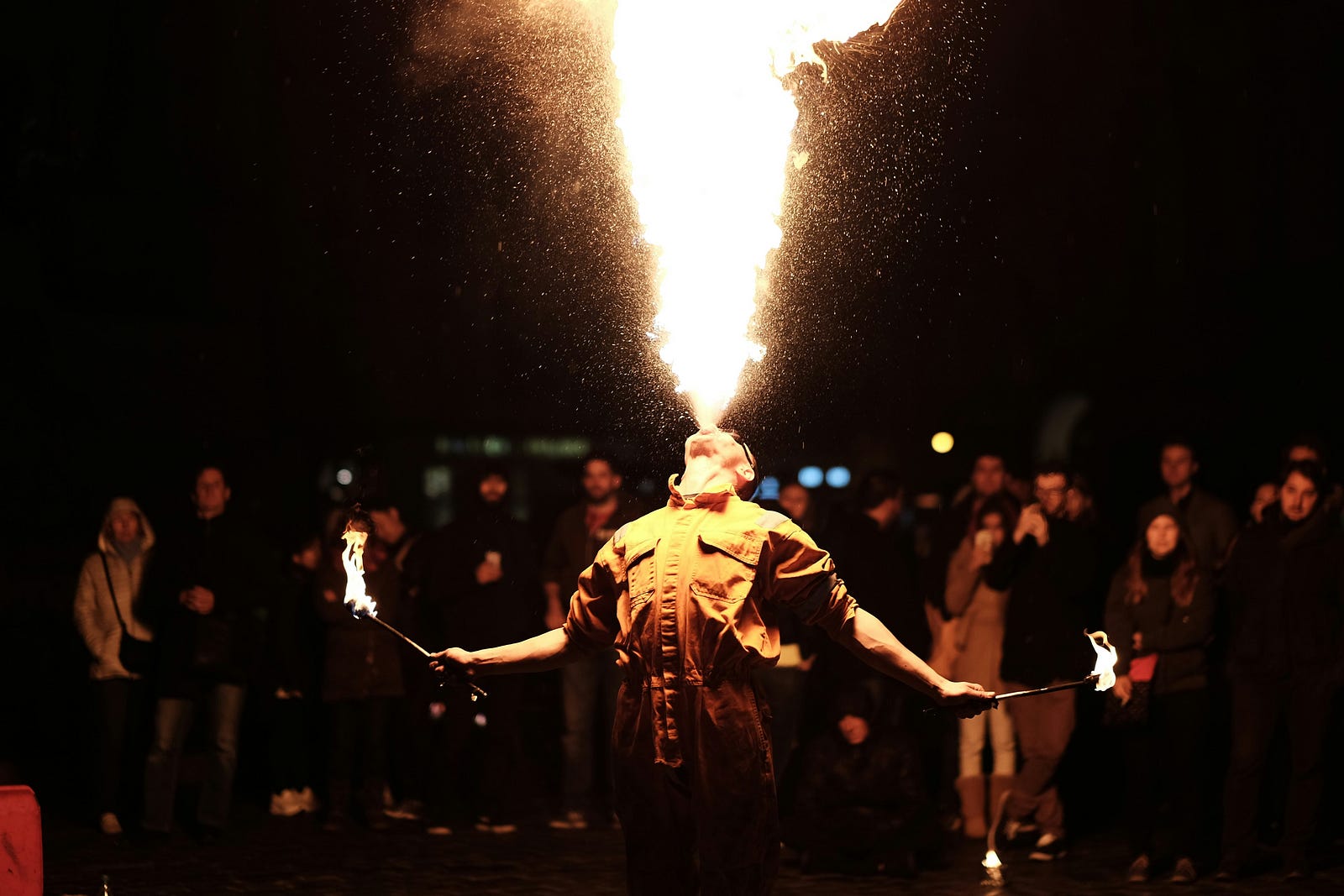 A man spits fire skyward at night.