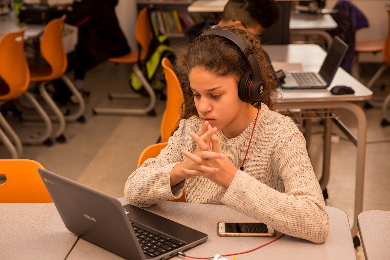 A student sits at a computer with headphones on so they can hear CommonLit’s Read Aloud of a text.