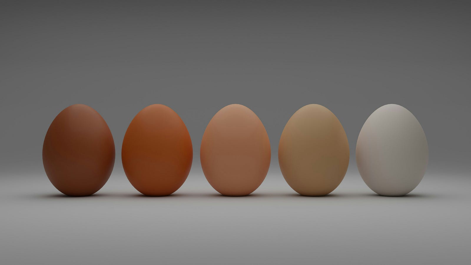 Five eggs, standing on end and arrayed from left to right. The first is dark brown; the colors progressively lighten from left to right.