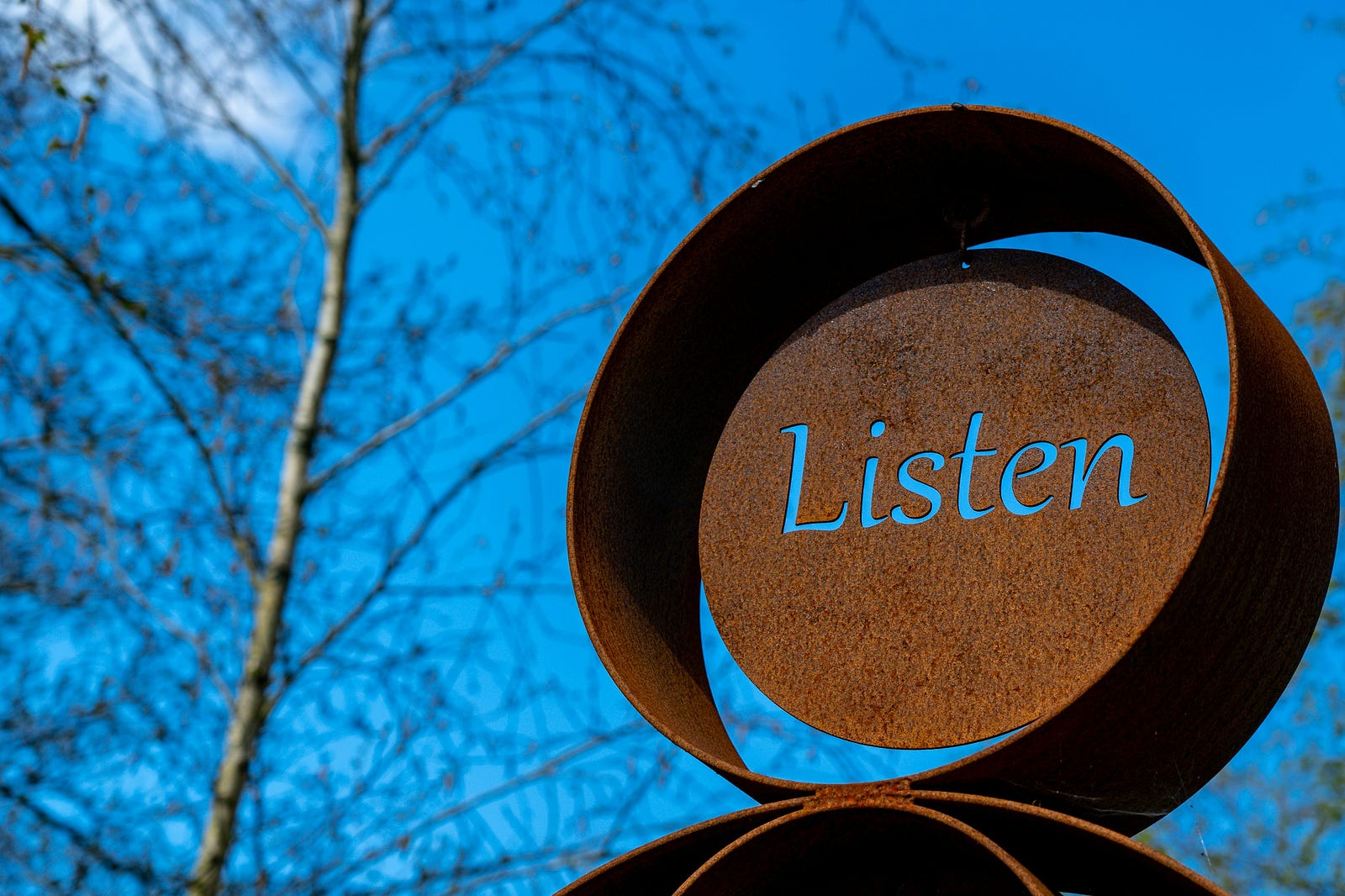 A metal round sculpture reads “Listen.”