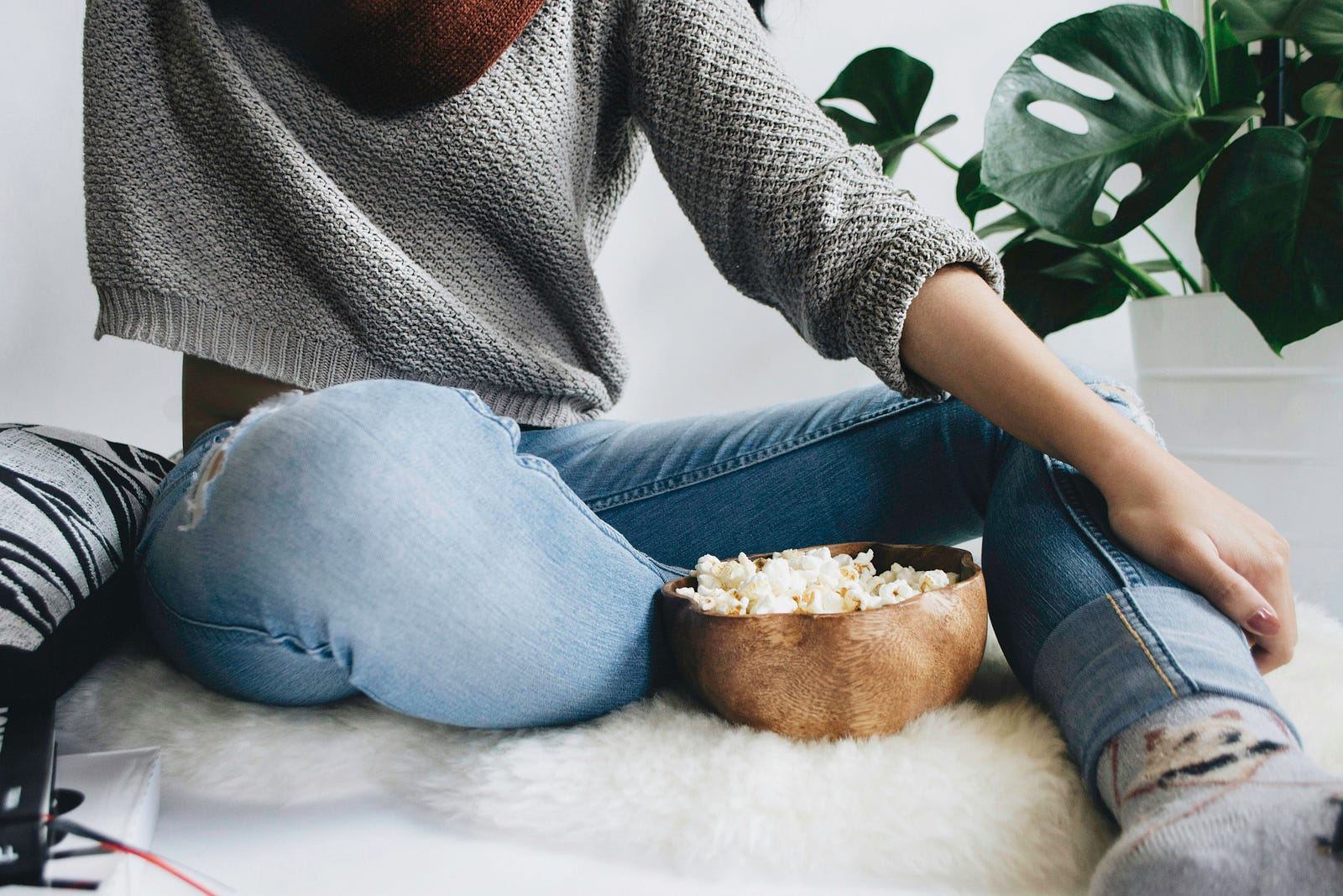 A woman sits with a bowl of popcorn on a sofa.
