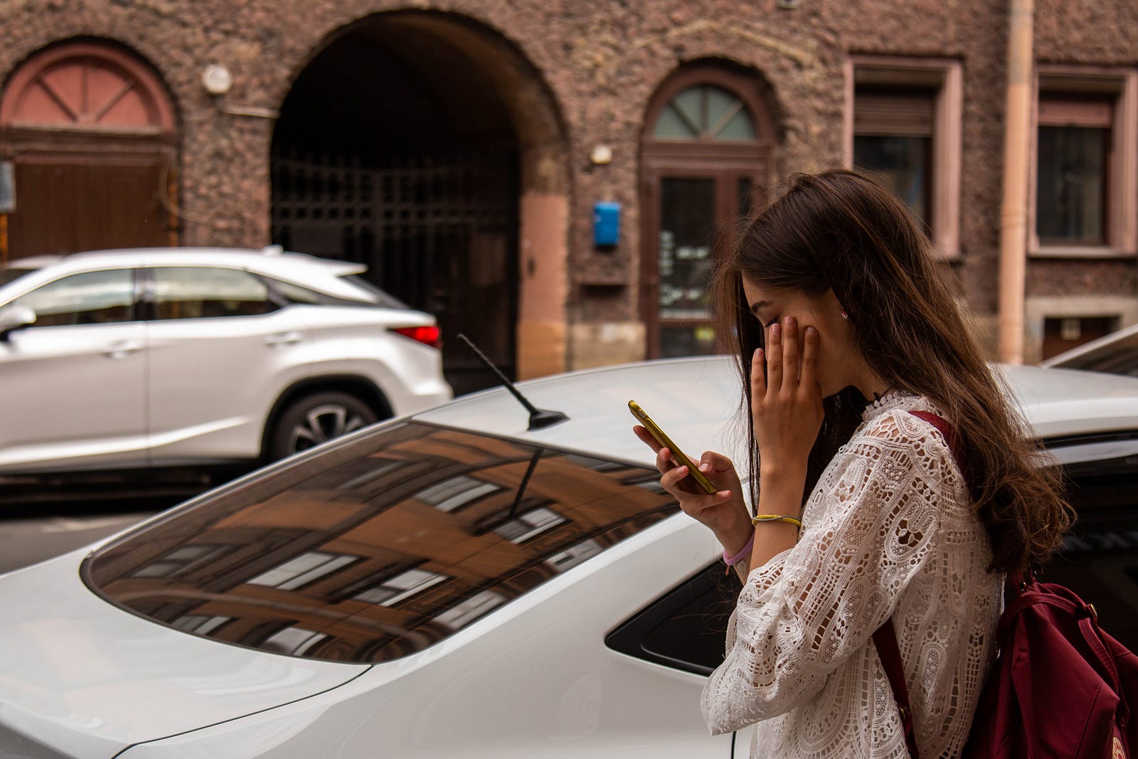 girl on her phone next to a car