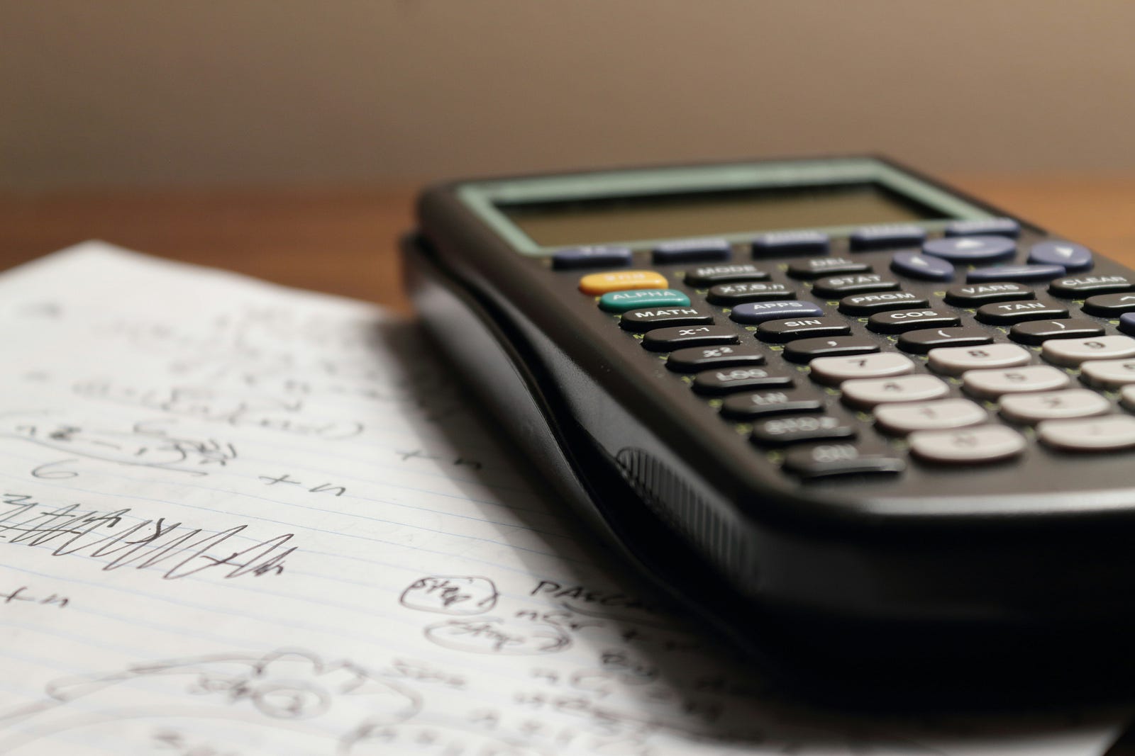 A calculator with a piece of paper beneath it.