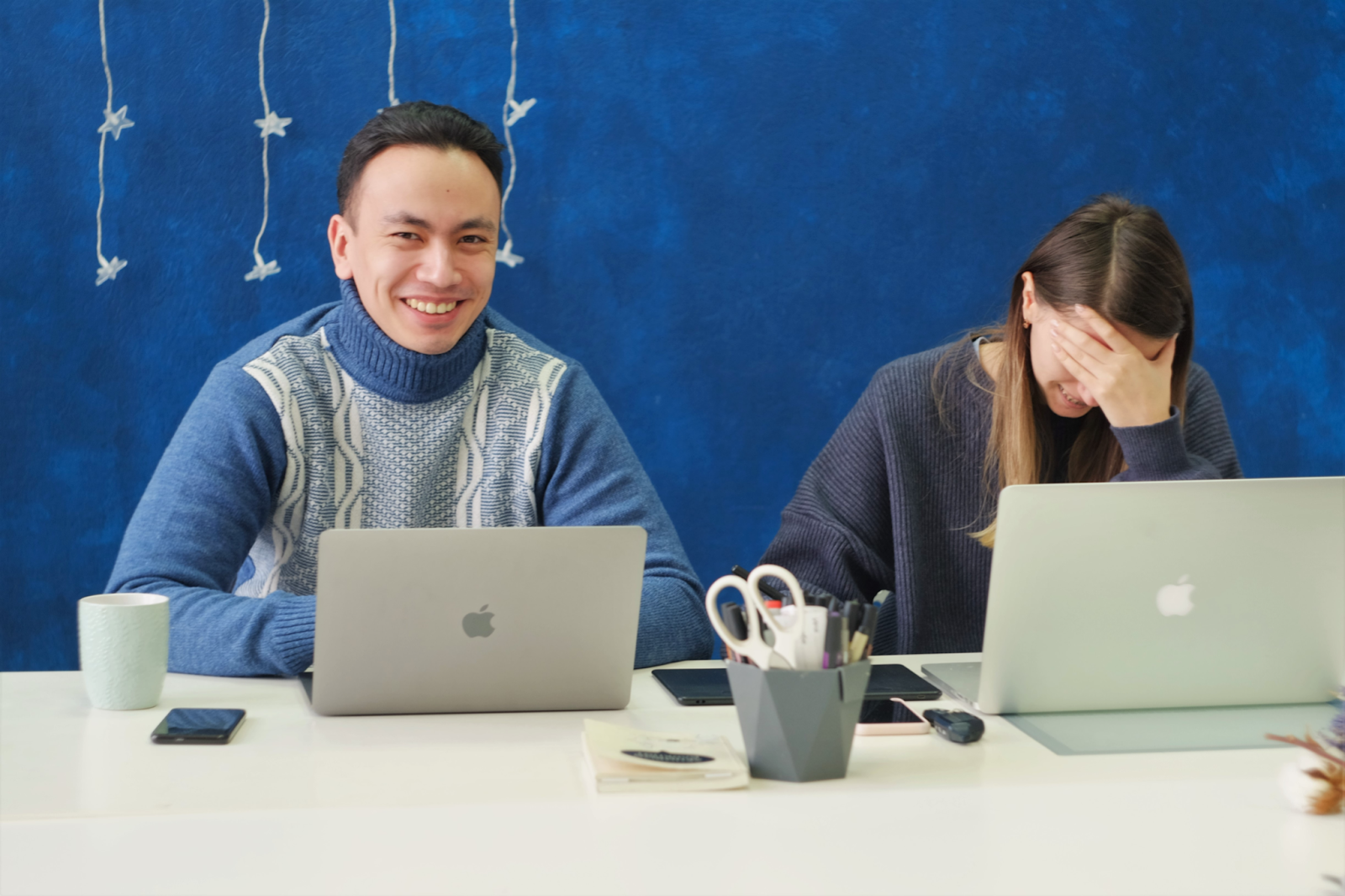 man and woman working on laptop laughing