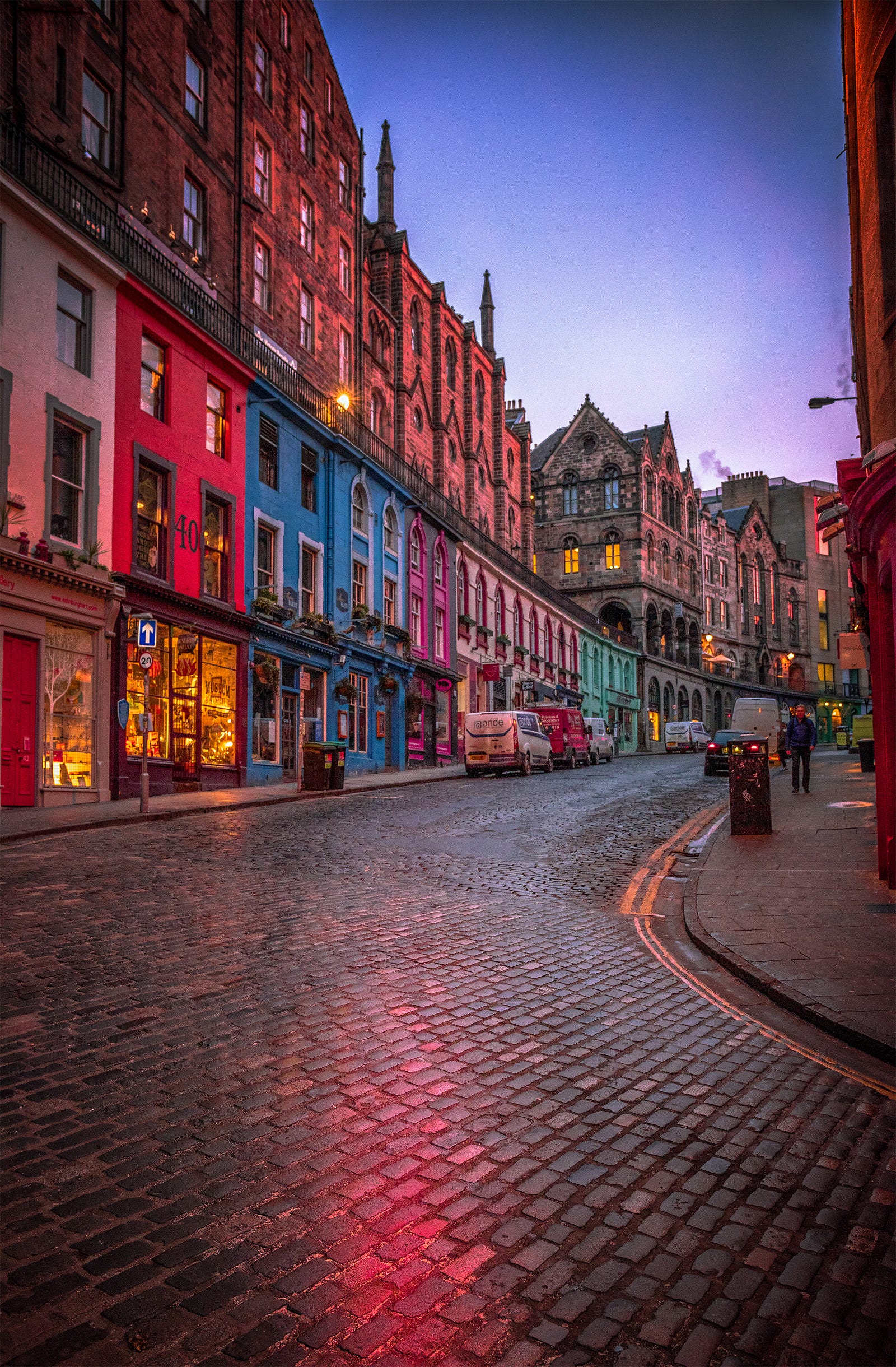 A photo of colorful buildings (and wet pavement) lining a slope in Edinburgh, Scotland. By walking uphill, you engage more muscles, particularly in your lower body, and increase the intensity of your walk. This activity helps build strength and endurance.