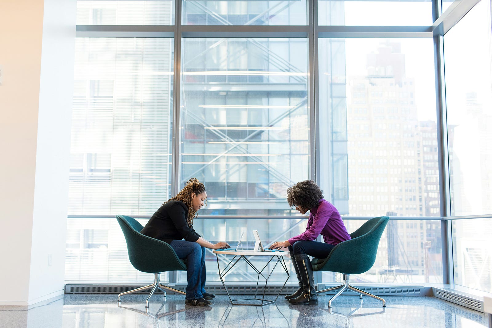 Two workers sit across from one another at a glass table. Sedentary behavior is associated with poor health outcomes, including early mortality.