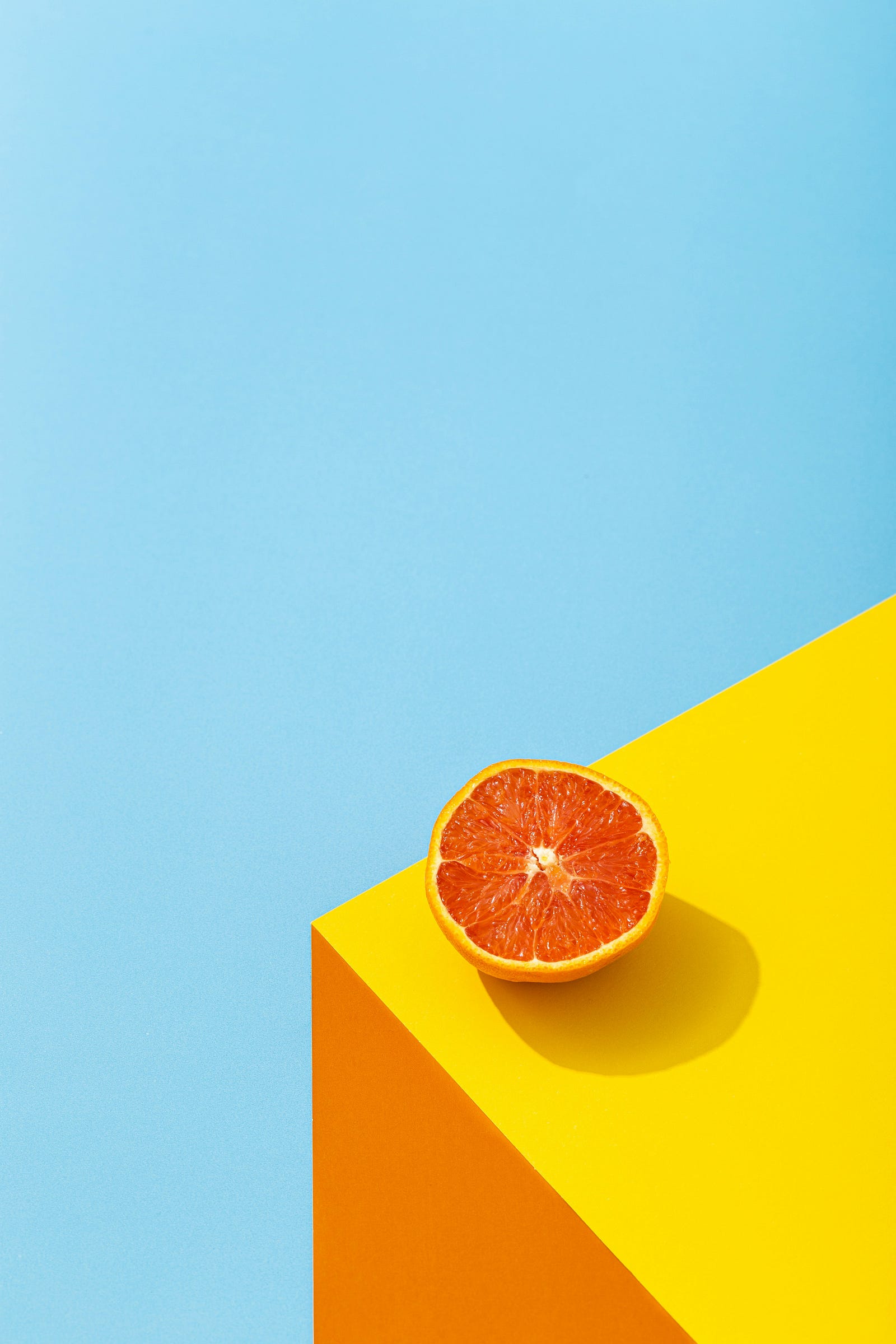 A colorful drawing of an orange perched on the edge of a bright yellow table.