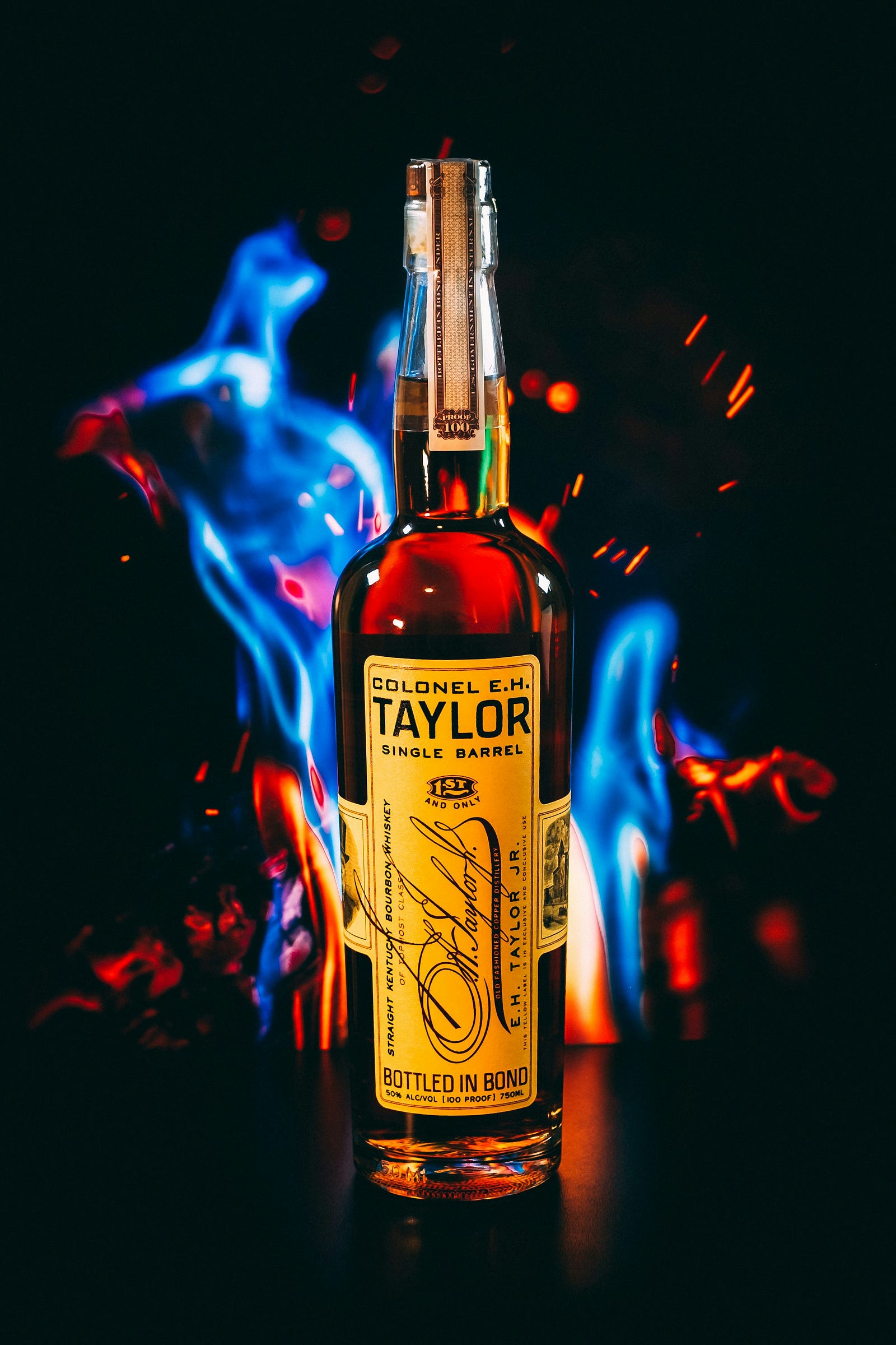 A bottle of Colonel E.H. Taylor whiskey, with blue flames behind it.