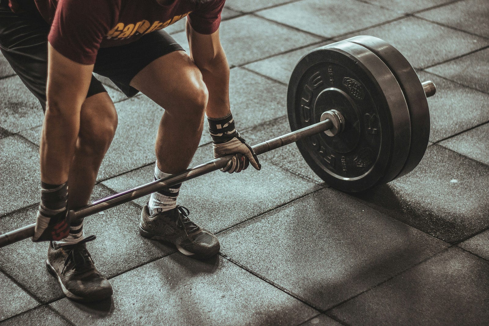 A man bends over to grab a barbell with weights.