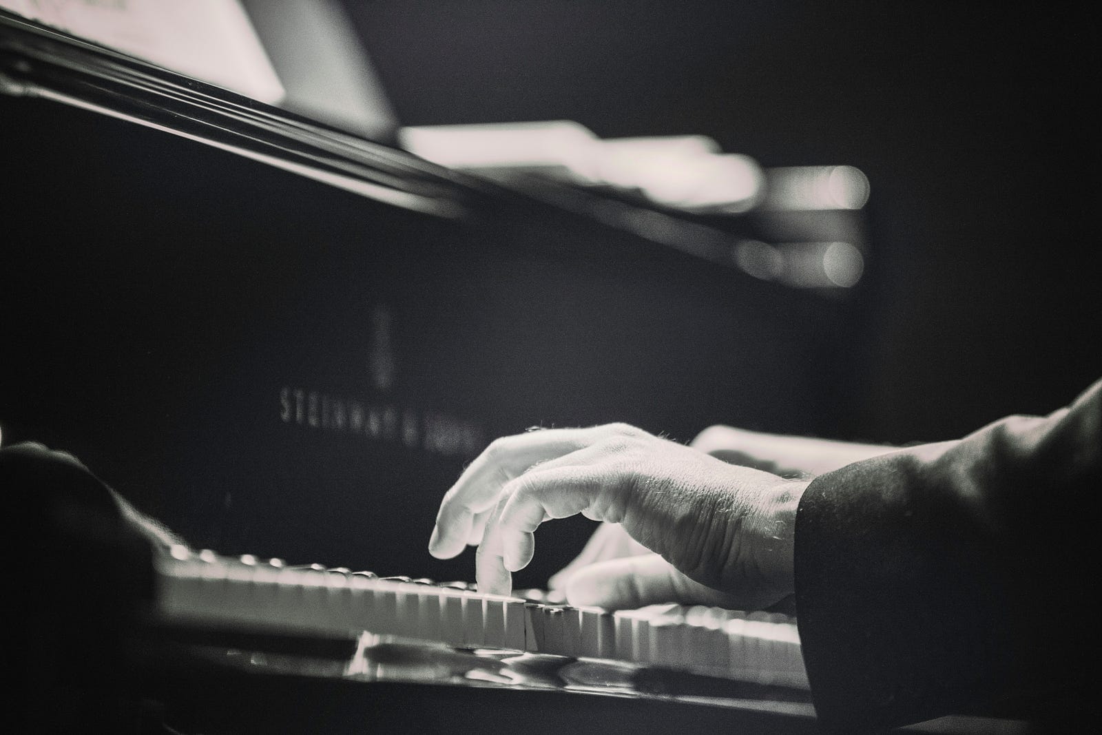 Closeup of a person playing a Steinway piano.