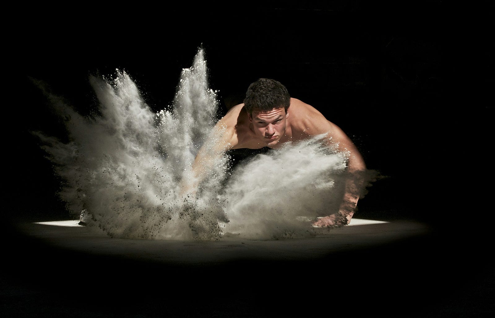 A man smashes the floor, sending chalk flying in all directions.