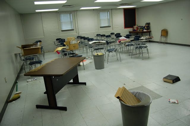 A basement classroom in disrepair with bare walls. 