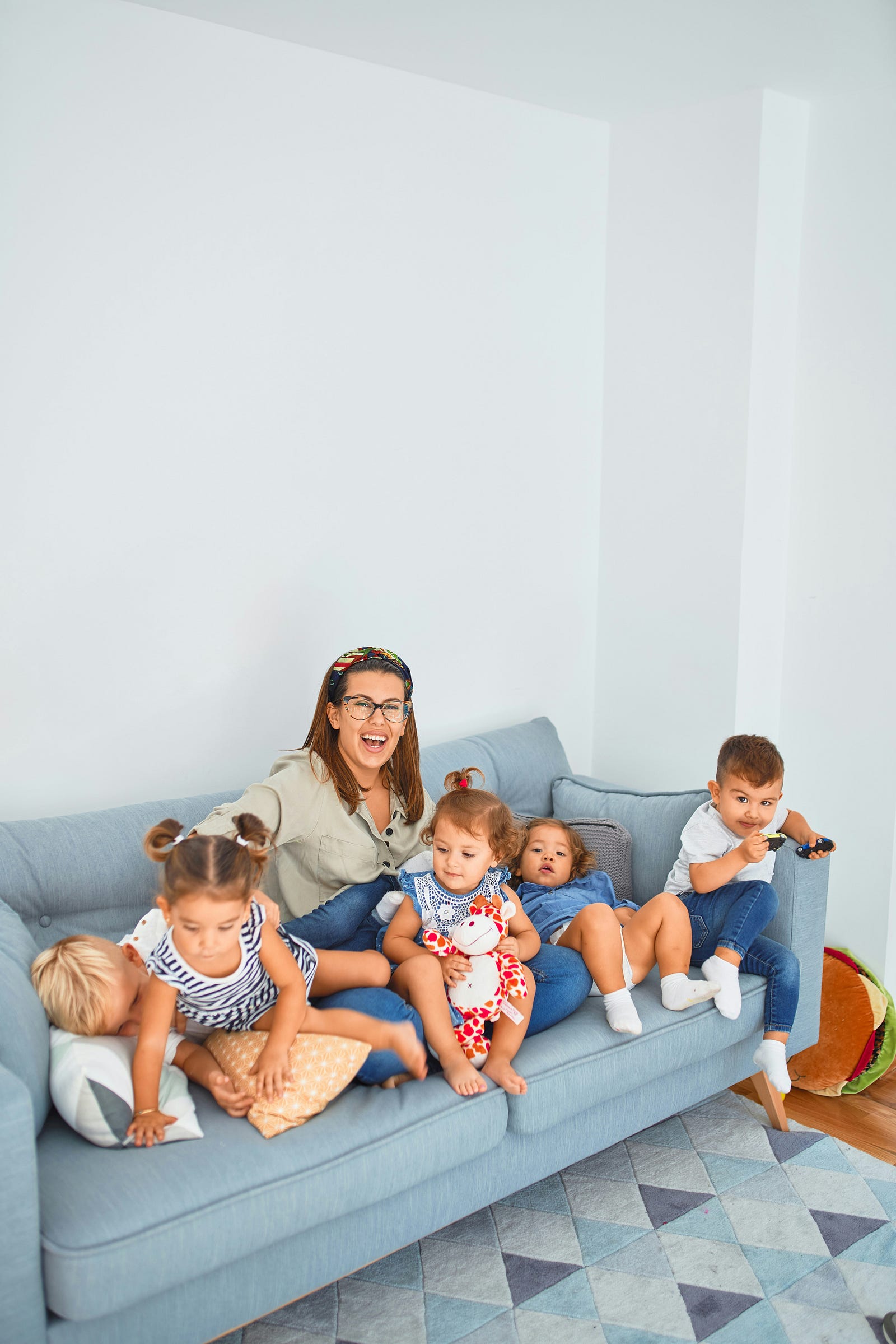 A group of children sit with a caregiver on a sofa. Children can also be affected by long COVID, although it appears to be more prevalent in adults.