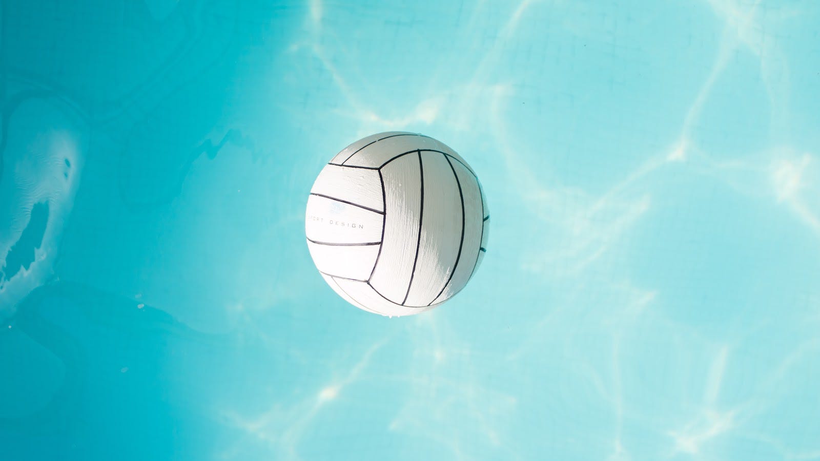 Volleyball floats up against a blue sky with clouds. 