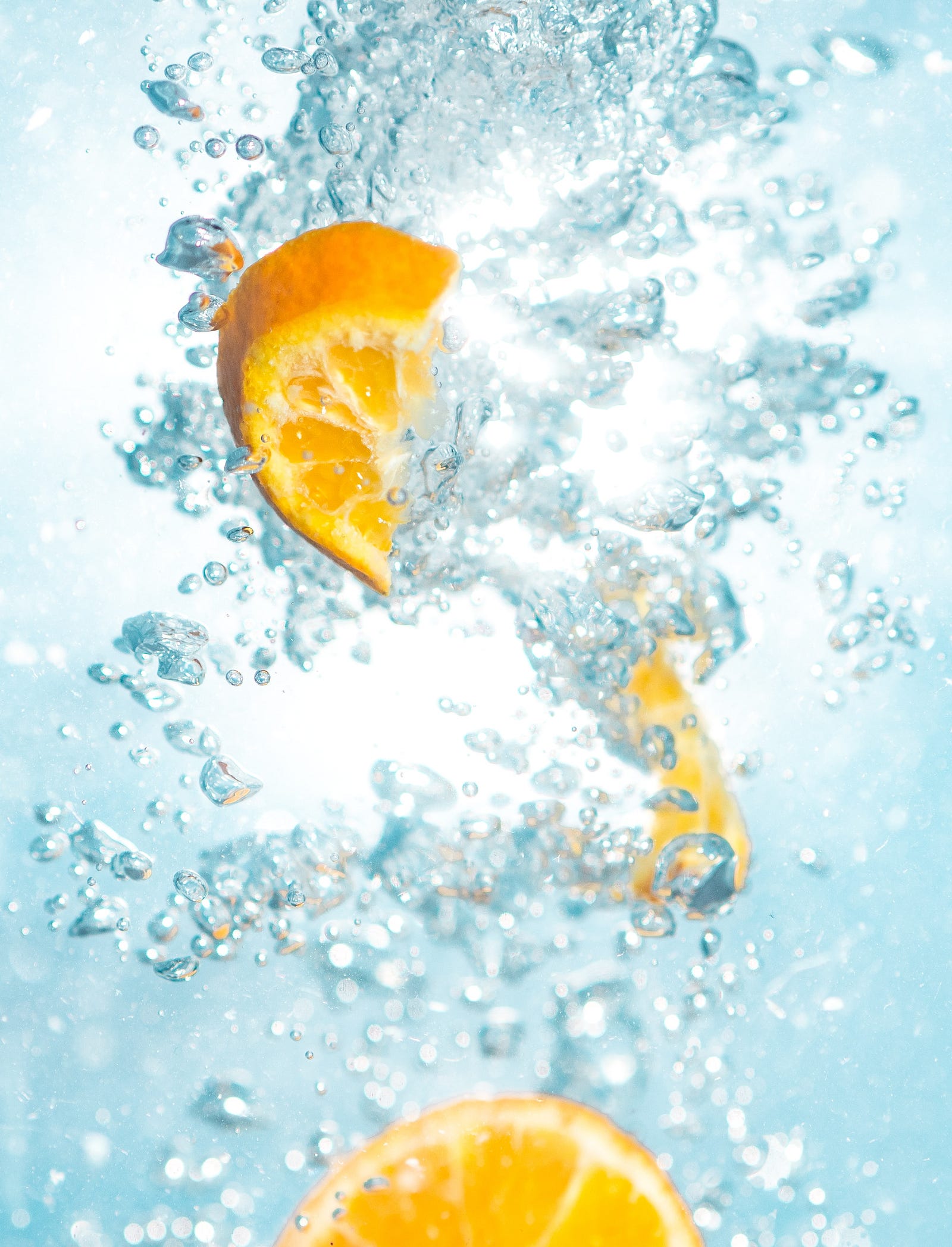 Three orange slices float (at different heights) in sparkling water. A Korean study showed that carbonated water negatively affects etched or sealed enamel, resulting in decreased microhardness and removal of the adhesive material.