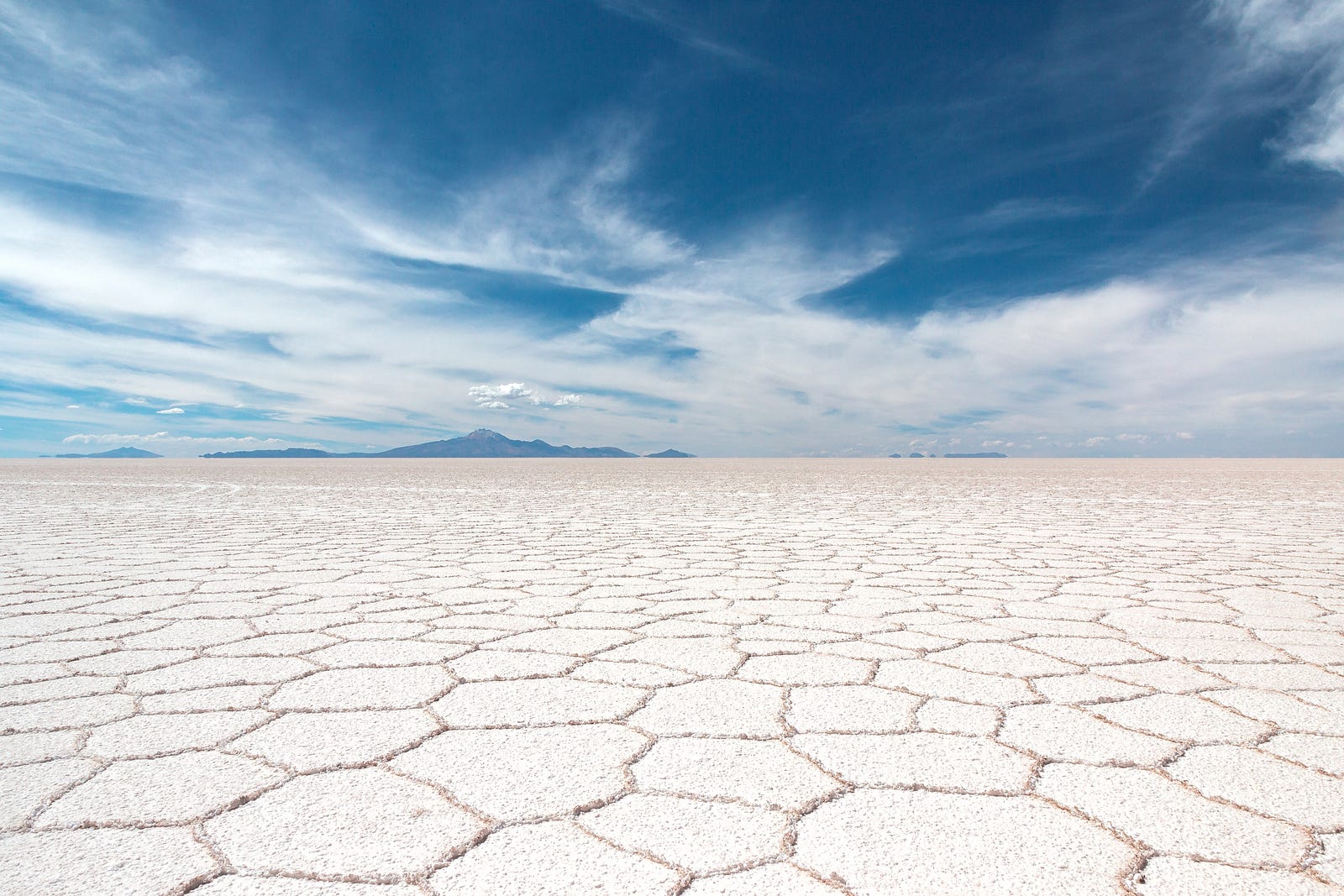 We see a salt field, naturally divided into pentagonal shapes. There is a vibrant sky with clouds in the upper third of the image. Nine out of 10 Americans take in too much sodium. This excess is often in processed, fast, and restaurant meals.