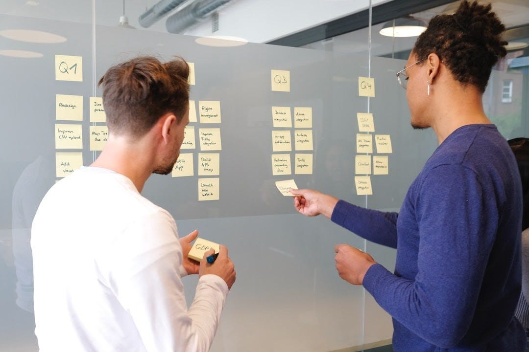 employees collaborating through post-it notes board