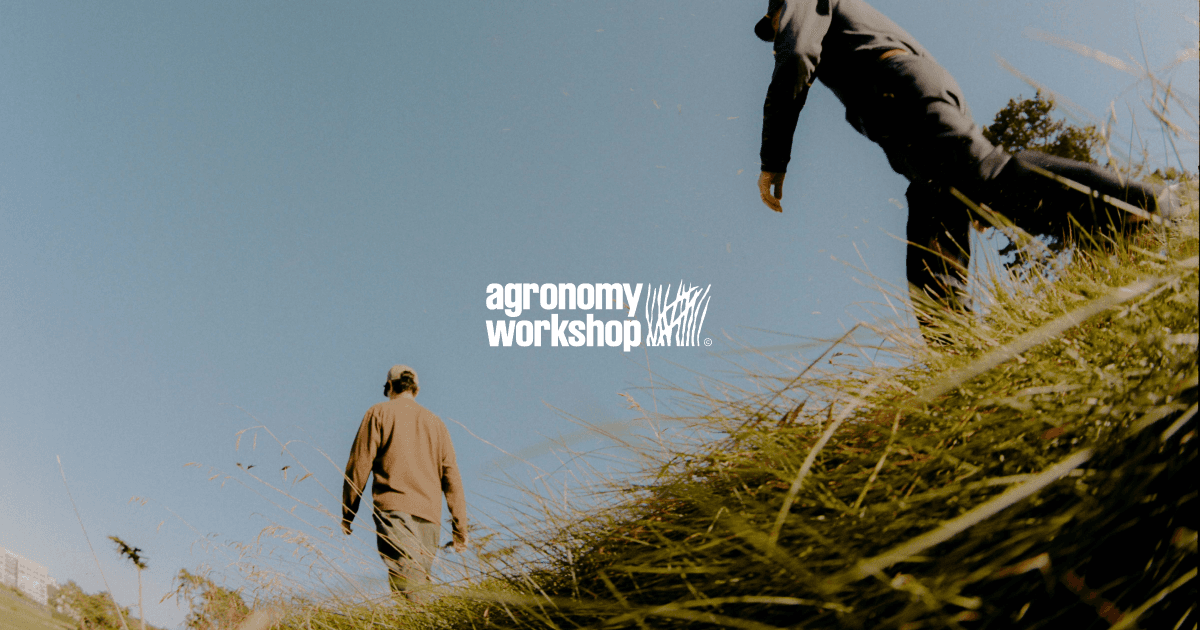 Agronomy Workshop website hero showing two people walking through a grassy field under clear sky with natural, documentary-style photography