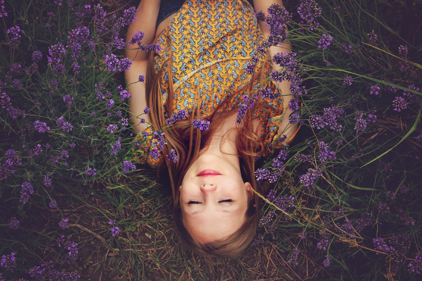 A young woman is upside down in the image. Her eyes are closed as she lies ina field of purple flowers. In a recent study, those regularly consuming excessive dietary fat and sugar (junk food) experienced disruptions in their brain’s slow-wave sleep patterns.