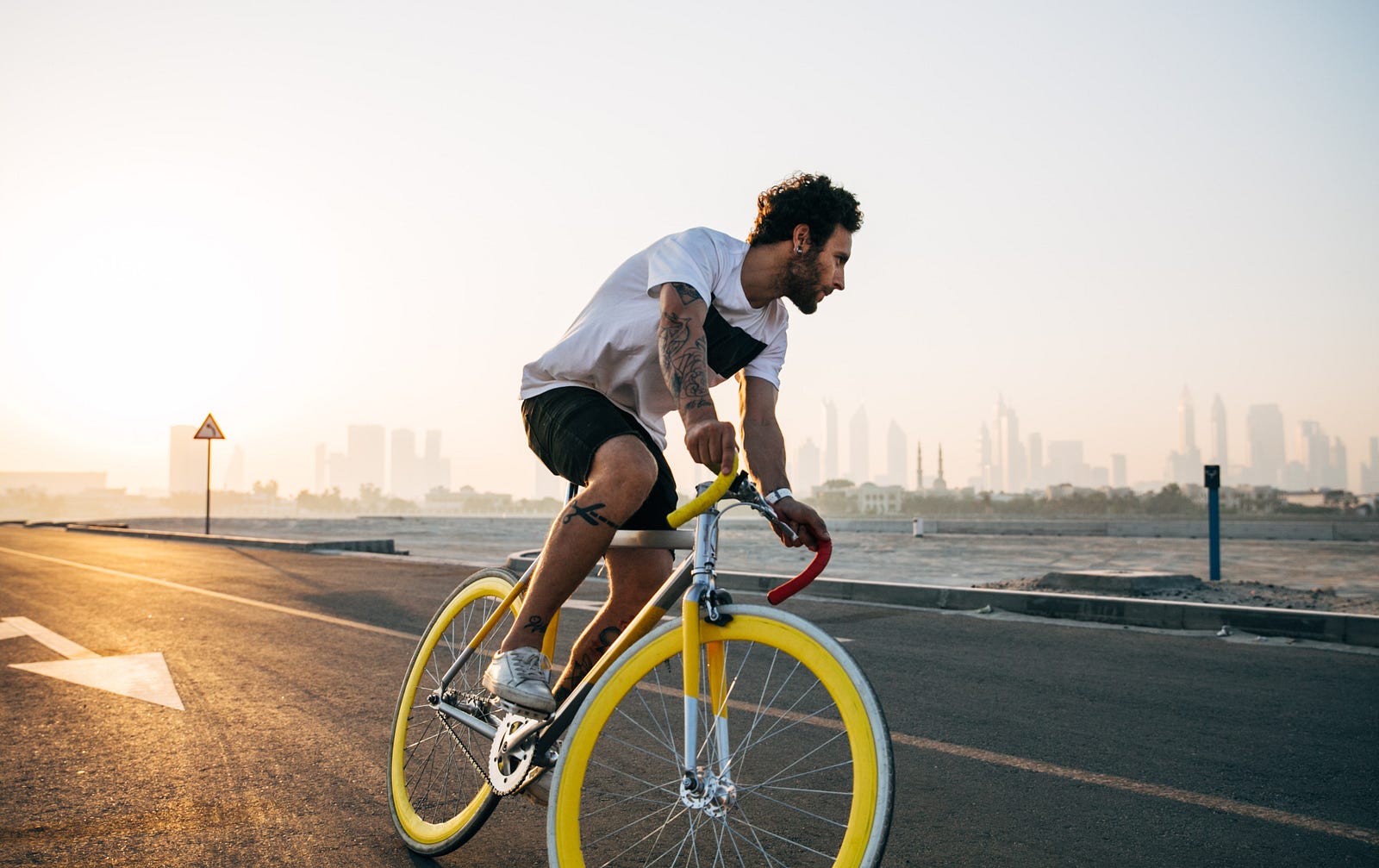 A man rides a racing bicycle with yellow tire rims.
