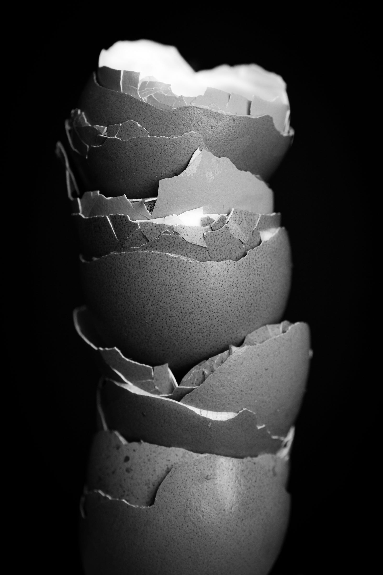 The bottom halves of cracked egg shelves are stacked high. Black and white photo with a dark black background. The egg diet is trending on TikTok, but this weird diet does not work (an eagg only (with tea) diet is unhealthy and not sustainable).