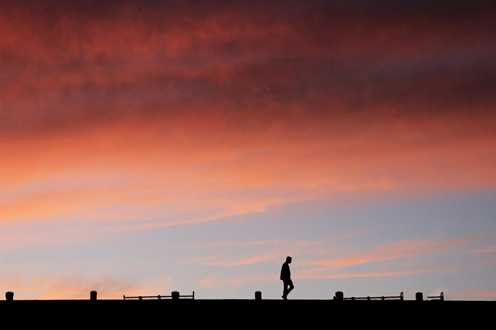 A person walks in the distance, with a sunset sky behind them.